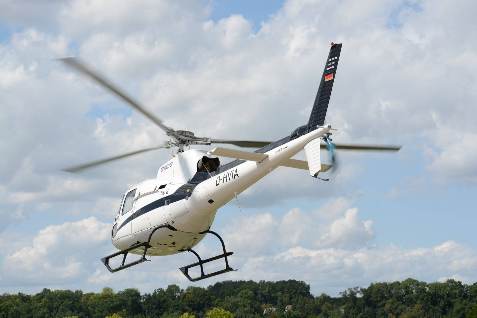 Weißer Hubschrauber AS350 kurz nach dem Abheben vor blauem Himmel